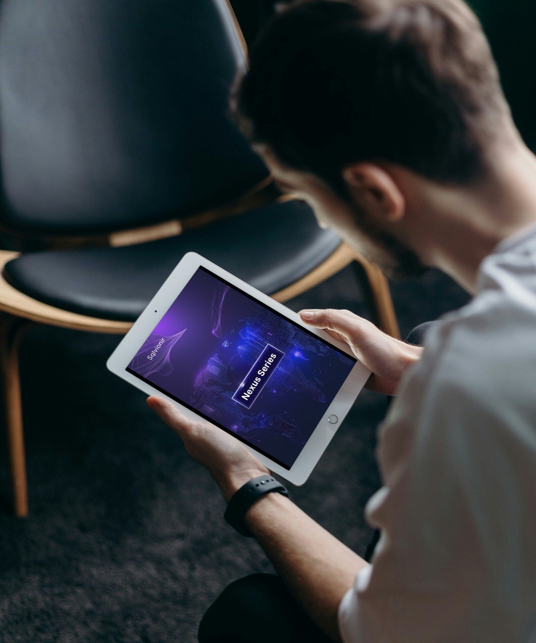 Person using a tablet in a dimly lit room with chairs.