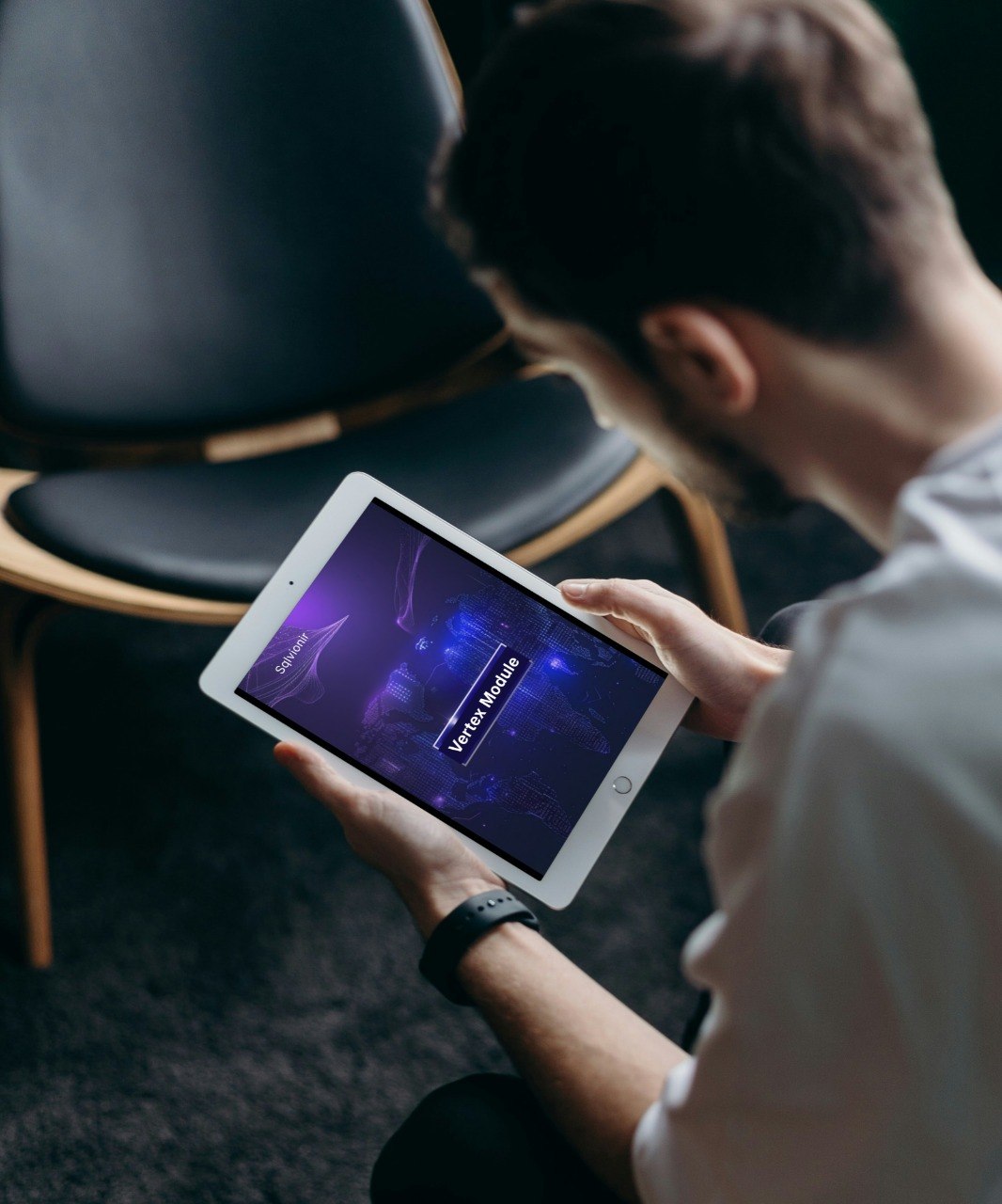 Person using a tablet in a dimly lit room with chairs.